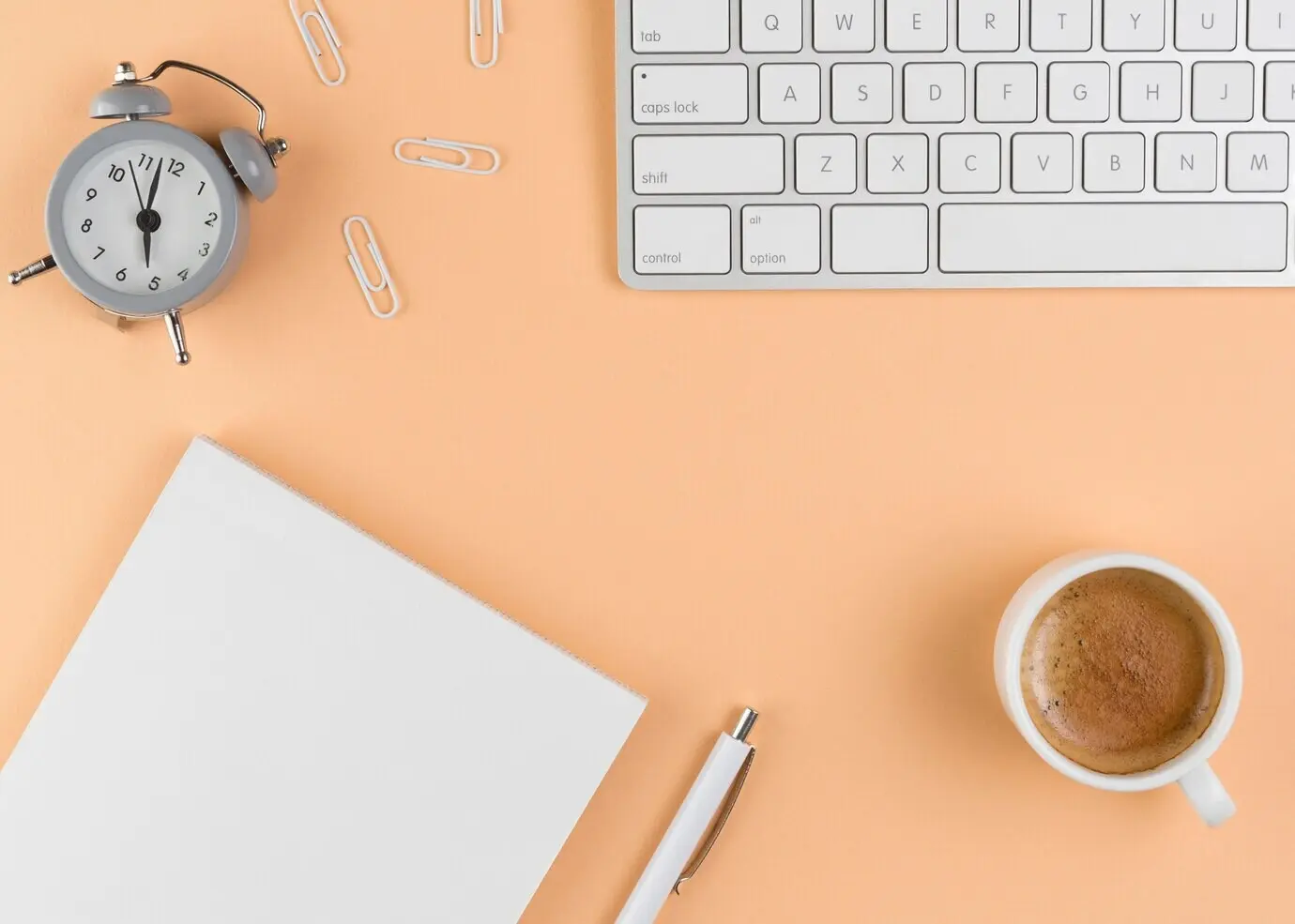 Overhead view of a desk with a keyboard and a clock.
